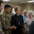 a female chaplain in a group of people including men in military uniform and others in ordinary clothes.